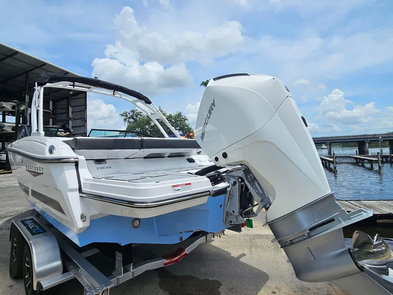 Slide: The Image of 2025 Monterey 235SS boat with Mercury outboard engine, docked near a marina under a cloudy sky. - 3