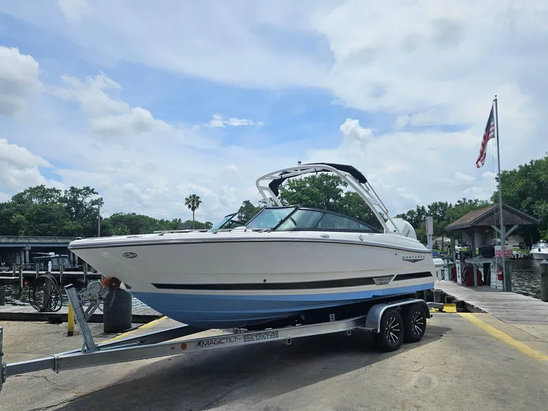 Slide: The Image of 2025 Monterey 235SS boat on trailer at dock, under a partly cloudy sky. - 5
