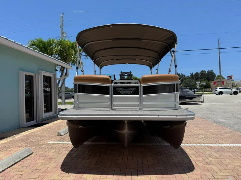Slide: The Image of 2026 Bennington 24 MSB pontoon boat with canopy, parked on brick pavement under clear blue sky. - 2