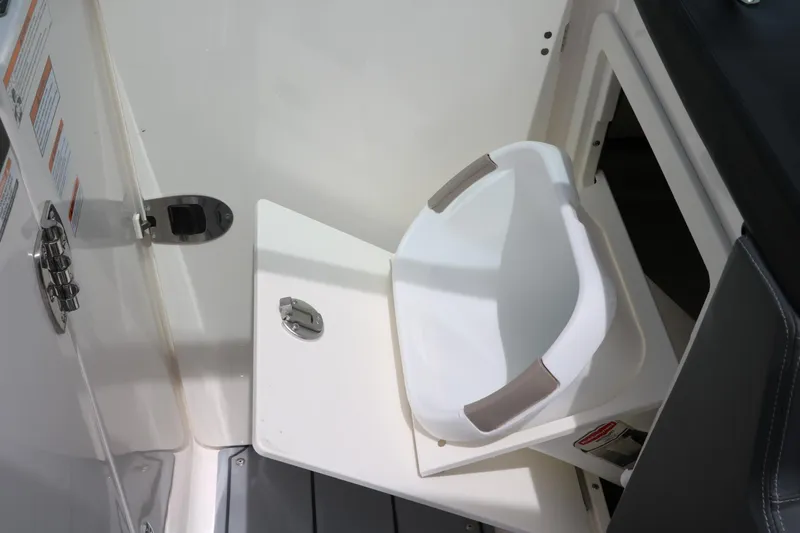 Slide: The Image of 2025 Chaparral 267 SSX boat interior with a white seat and storage compartment. - 22