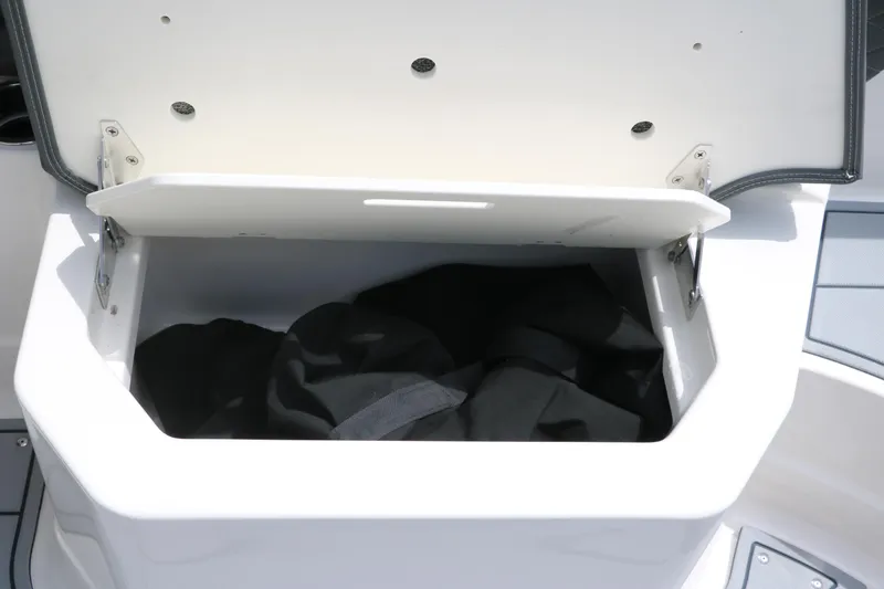 Slide: The Image of Open storage compartment on 2025 Chaparral 267 SSX boat, containing black fabric. - 24