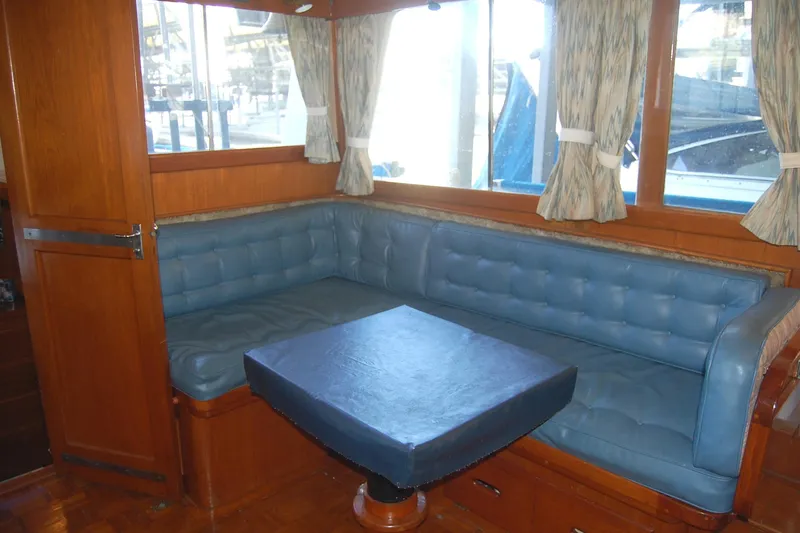 Slide: The Image of 1983 Island Gypsy 36 Quad Cabin interior with blue cushioned seating and wooden accents. - 12