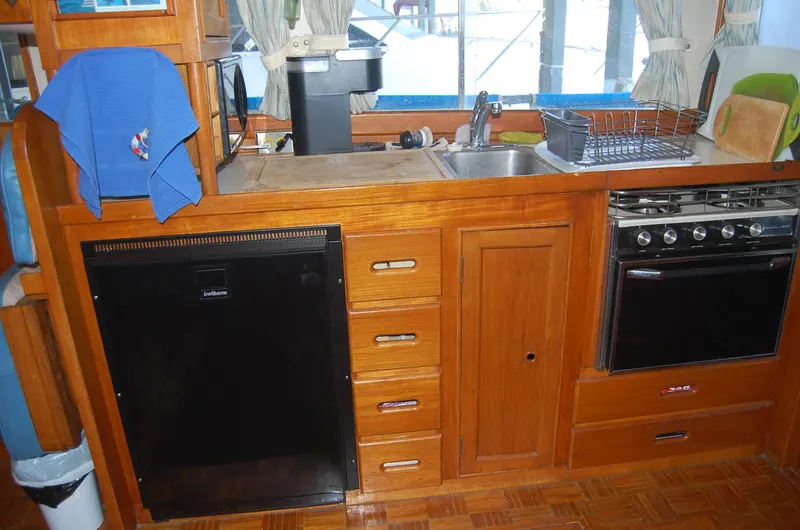 Slide: The Image of 1983 Island Gypsy 36 Quad Cabin kitchen with wooden cabinetry, sink, stove, and refrigerator. - 15