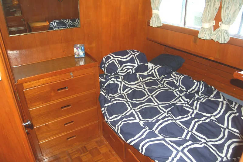 Slide: The Image of Cozy cabin interior of 1983 Island Gypsy 36 Quad, featuring wooden furniture and patterned bedding. - 2