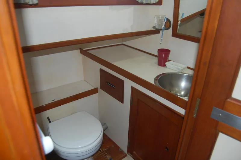 Slide: The Image of 1983 Island Gypsy 36 Quad Cabin bathroom with sink, toilet, and wooden cabinetry. - 27