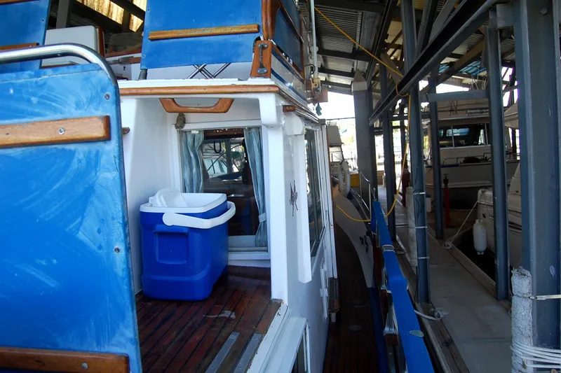 Slide: The Image of 1983 Island Gypsy 36 Quad Cabin docked, featuring blue cooler and wooden deck. - 29