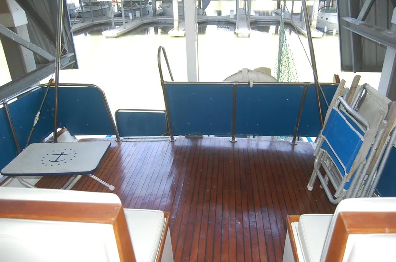 Slide: The Image of 1983 Island Gypsy 36 Quad Cabin deck with wooden flooring and blue seating. - 35