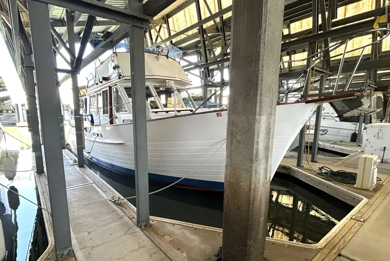 Slide: The Image of 1983 Island Gypsy 36 Quad Cabin docked in a covered marina. - 7