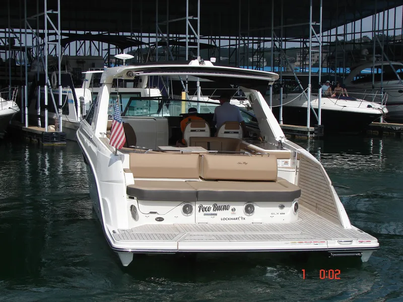 Slide: The Image of 2018 Sea Ray SLX 400 boat docked at marina, rear view with seating and American flag. - 31