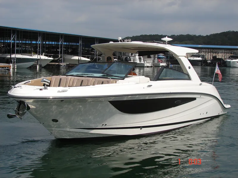 Slide: The Image of 2018 Sea Ray SLX 400 boat on water, docked near marina, with American flag. - 37