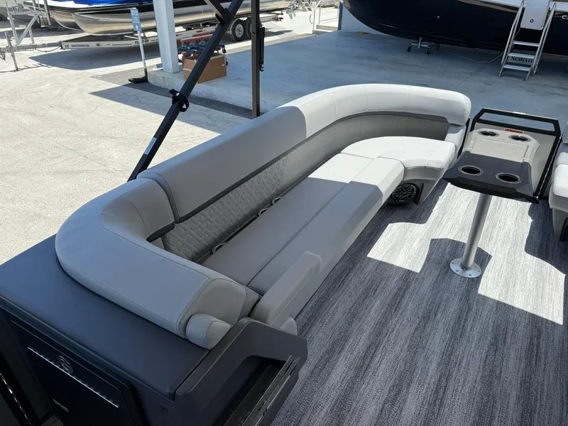 Slide: The Image of 2026 Bennington 26 MFB boat interior with gray seating and table, docked outdoors. - 21