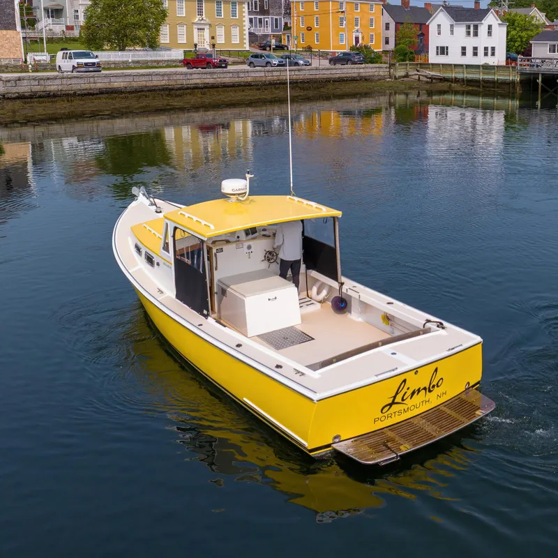 Slide: The Image of Yellow 2008 Holland Open boat named "Limbo" on calm water near colorful buildings. - 6