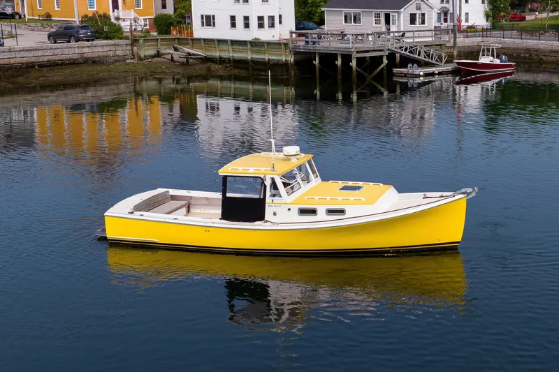 Slide: The Image of Yellow 2008 Holland Open boat on calm water near dockside buildings. - 8