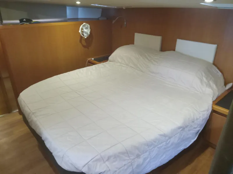 Slide: The Image of 2016 Aquila 44 cabin interior with a cozy double bed and wooden paneling. - 25