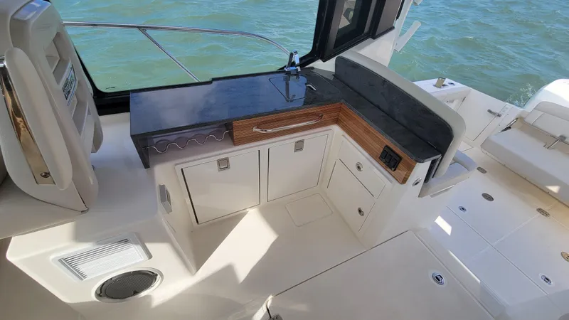 Slide: The Image of 2021 Boston Whaler 405 Conquest boat interior with kitchenette and seating area. - 12