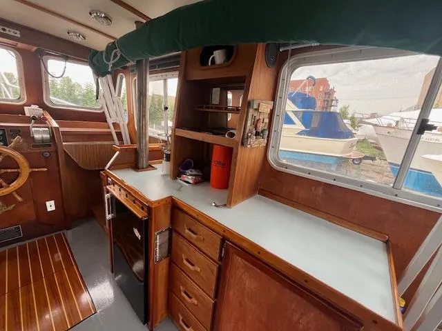 Slide: The Image of 1989 Maritime 340 Trawler interior with wooden cabinetry and helm, docked near other boats. - 28