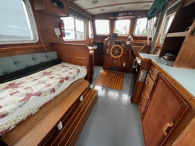 Slide: The Image of 1989 Maritime 340 Trawler interior with wooden finish, steering wheel, and cozy sleeping area. - 29