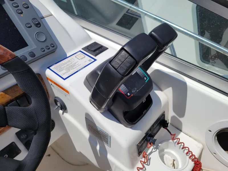 Slide: The Image of Control panel of a 2003 Larson 310 boat, featuring throttle and steering wheel. - 14