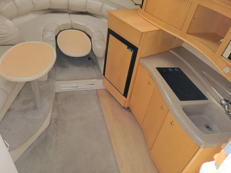 Slide: The Image of 2003 Larson 310 boat interior with kitchenette, seating area, and compact design. - 18