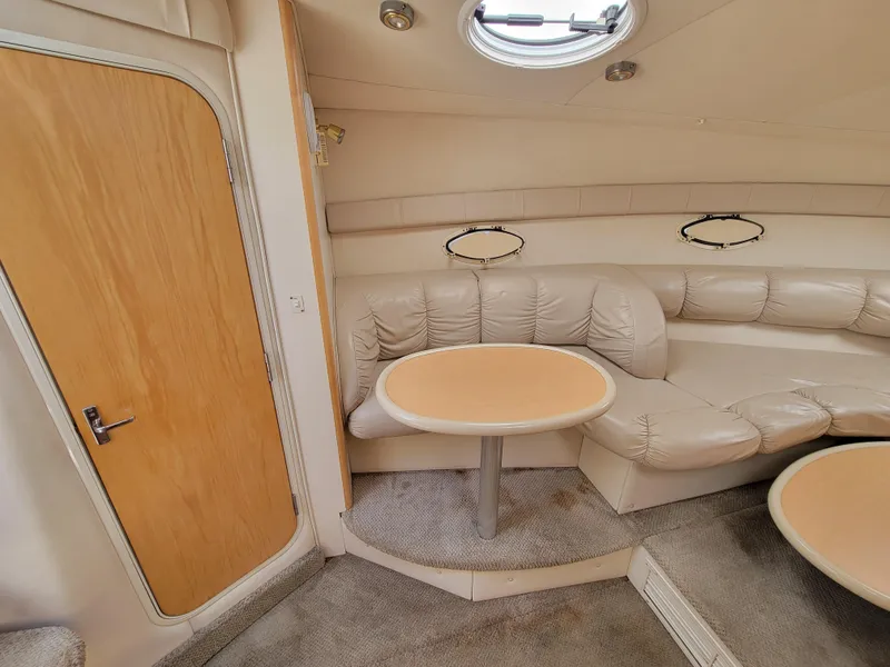 Slide: The Image of 2003 Larson 310 boat interior with beige leather seating and round table. - 21