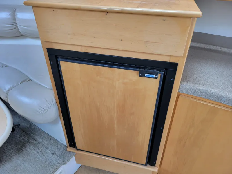 Slide: The Image of Wooden cabinet with a built-in mini fridge on a 2003 Larson 310 boat. - 24