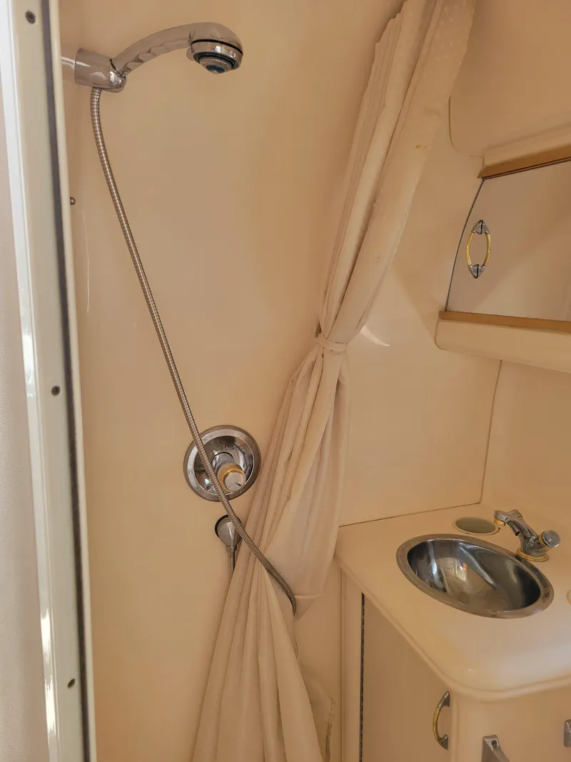 Slide: The Image of 2003 Larson 310 boat bathroom with shower, sink, and curtain. - 30