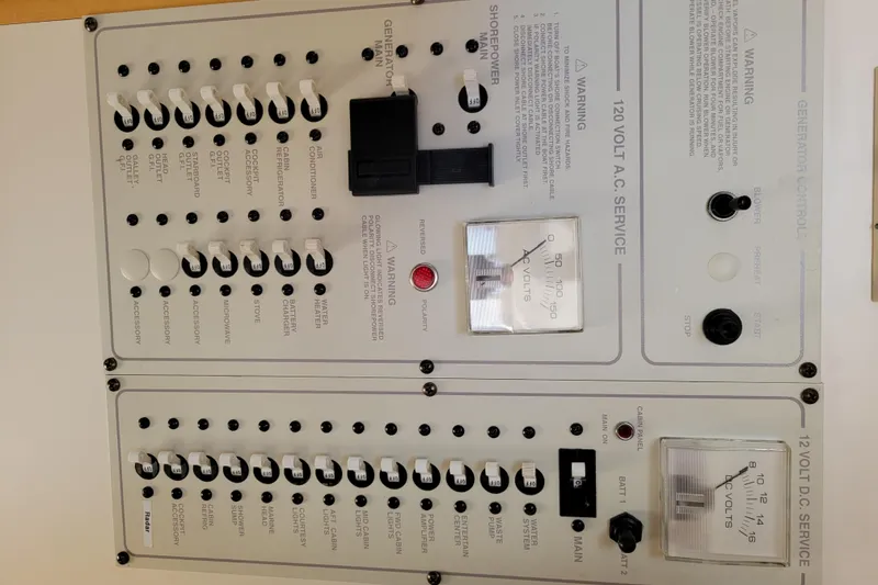 Slide: The Image of Electrical panel of a 2003 Larson 310 boat, featuring AC and DC service controls. - 33