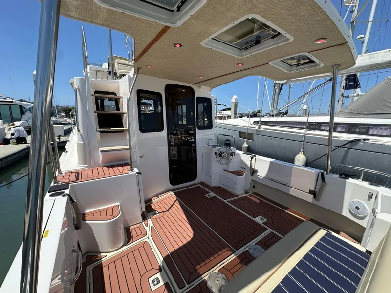 Slide: The Image of 2023 Ranger Tugs R-31 CB boat interior with wood flooring and seating at a marina. - 16