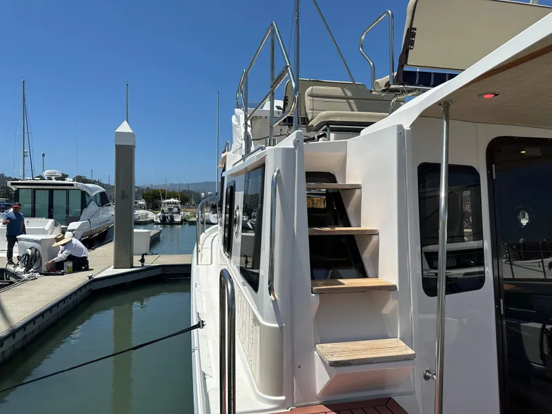 Slide: The Image of 2023 Ranger Tugs R-31 CB docked at marina, featuring exterior stairs and upper deck seating. - 17