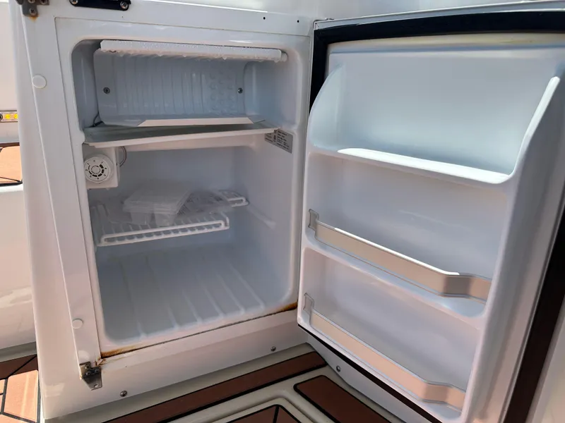 Slide: The Image of Open refrigerator inside 2023 Ranger Tugs R-31 CB boat, showing empty shelves and door compartments. - 21