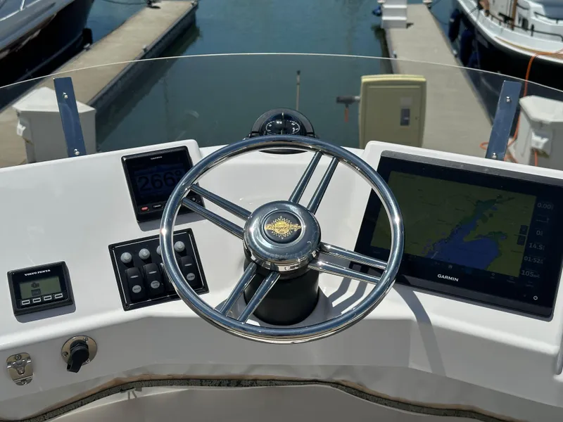 Slide: The Image of 2023 Ranger Tugs R-31 CB helm with steering wheel and navigation displays at marina. - 22