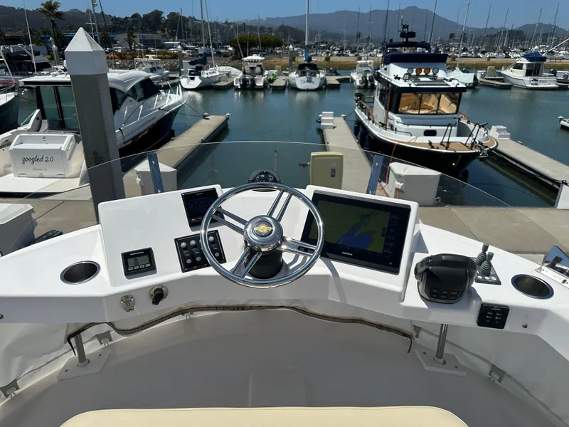 Slide: The Image of Cockpit view of 2023 Ranger Tugs R-31 CB at marina, featuring steering wheel and navigation screens. - 23