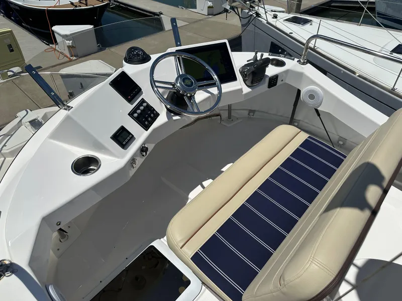 Slide: The Image of 2023 Ranger Tugs R-31 CB helm with modern controls and striped seating at a marina. - 24