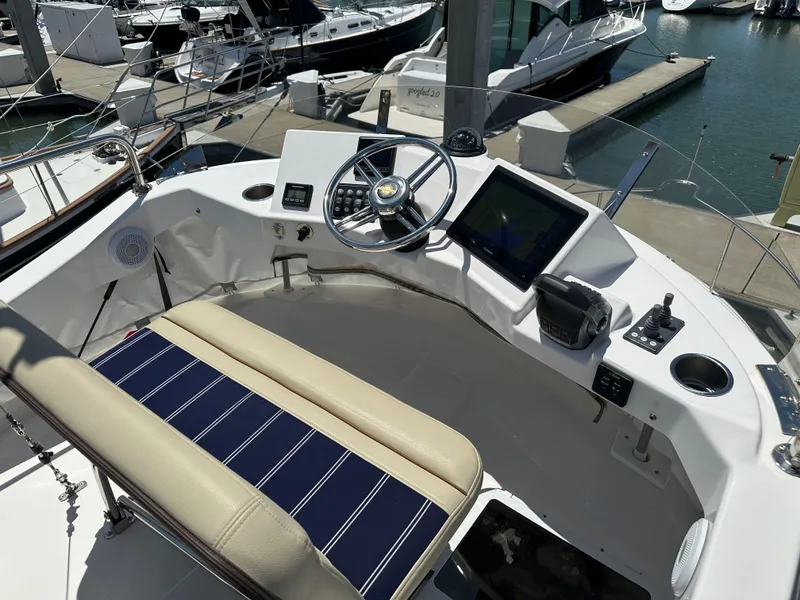 Slide: The Image of 2023 Ranger Tugs R-31 CB helm with modern controls and seating at marina. - 25