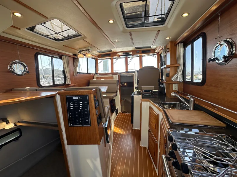 Slide: The Image of 2023 Ranger Tugs R-31 CB interior with wood accents, modern kitchen, and panoramic windows. - 38