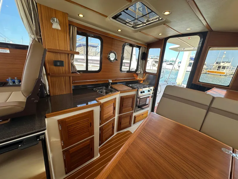 Slide: The Image of 2023 Ranger Tugs R-31 CB interior with wood finish, kitchen, and seating area. - 42
