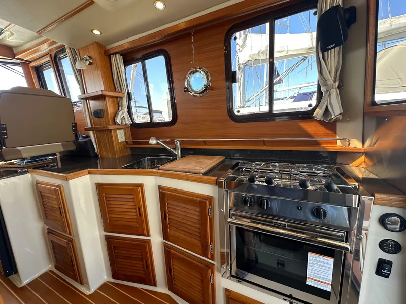 Slide: The Image of 2023 Ranger Tugs R-31 CB interior kitchen with wood cabinetry and stainless steel appliances. - 43