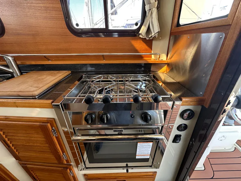 Slide: The Image of 2023 Ranger Tugs R-31 CB kitchen with stove and wooden cabinetry. - 44