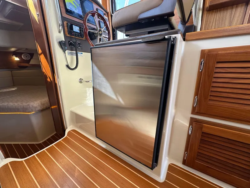 Slide: The Image of 2023 Ranger Tugs R-31 CB interior with stainless steel fridge and wooden cabinetry. - 47