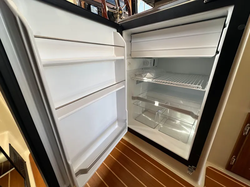 Slide: The Image of Open refrigerator inside 2023 Ranger Tugs R-31 CB boat, showcasing interior shelves and compartments. - 48