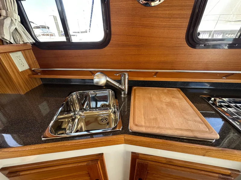 Slide: The Image of 2023 Ranger Tugs R-31 CB kitchen with sink, cutting board, and wood paneling. - 49