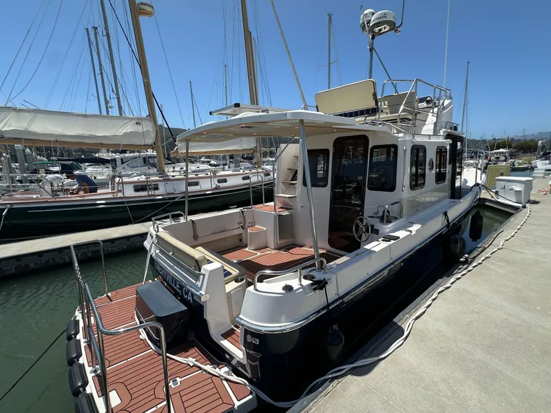 Slide: The Image of 2023 Ranger Tugs R-31 CB docked at marina, showcasing spacious deck and modern design. - 7
