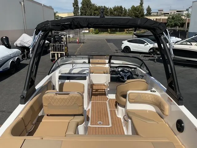 Slide: The Image of 2025 Bayliner VR6 Bowrider OB with tan seating and sleek design in a parking lot. - 18