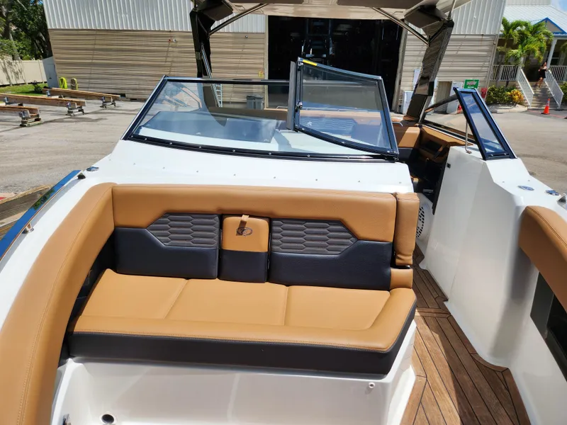 Slide: The Image of 2021 Cobalt A29 boat interior with tan and black seating, open windshield, and wooden flooring. - 17