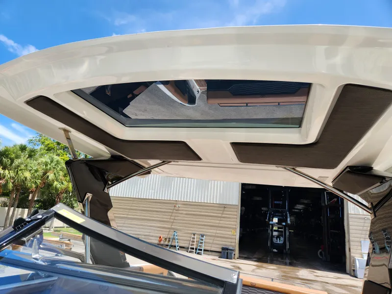 Slide: The Image of 2021 Cobalt A29 boat with open sunroof, docked near a warehouse under a clear blue sky. - 30