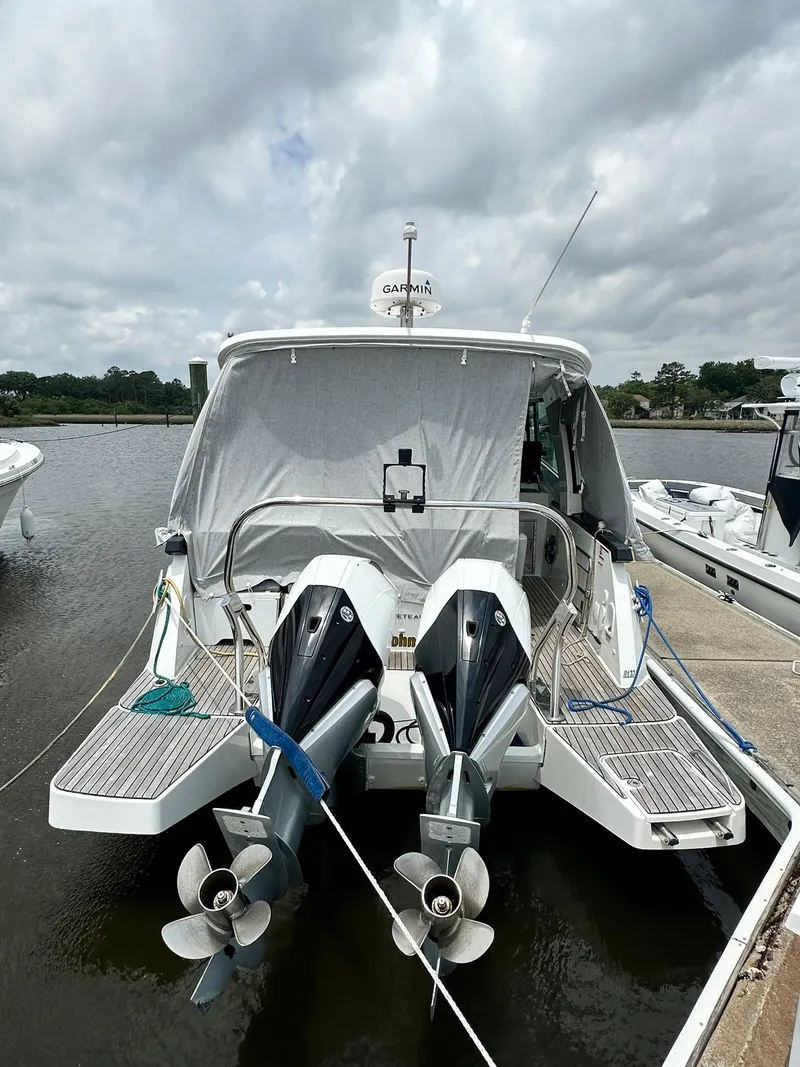 Slide: The Image of 2021 Beneteau GT 32 boat docked, featuring dual outboard motors, under a cloudy sky. - 4