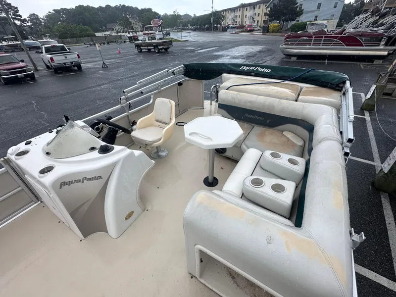 Slide: The Image of 2003 AquaPatio 240 RE pontoon boat with spacious seating and helm, parked in a marina. - 10