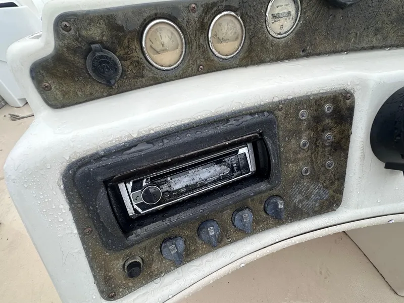 Slide: The Image of Control panel of a 2003 AquaPatio 240 RE boat, featuring gauges and a stereo system. - 13