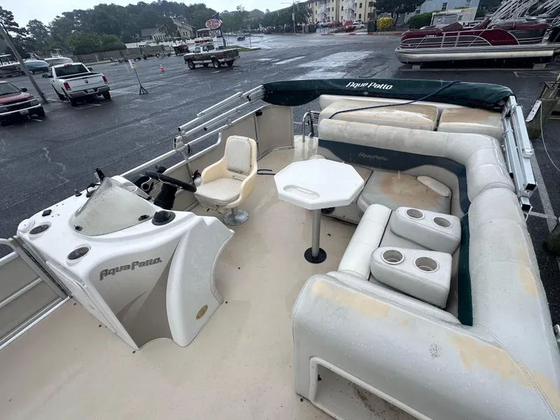 Slide: The Image of 2003 AquaPatio 240 RE pontoon boat with spacious seating and helm, parked in a marina. - 9