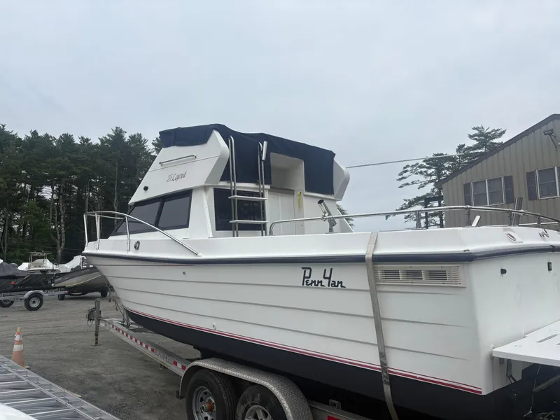 The Image of 1998 Penn Yan 269 Legend boat on trailer, parked outdoors near trees and building. - 0